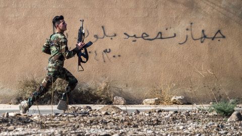A Peshmerga fighter runs to take position in the town of Bashiqa, near Mosul.