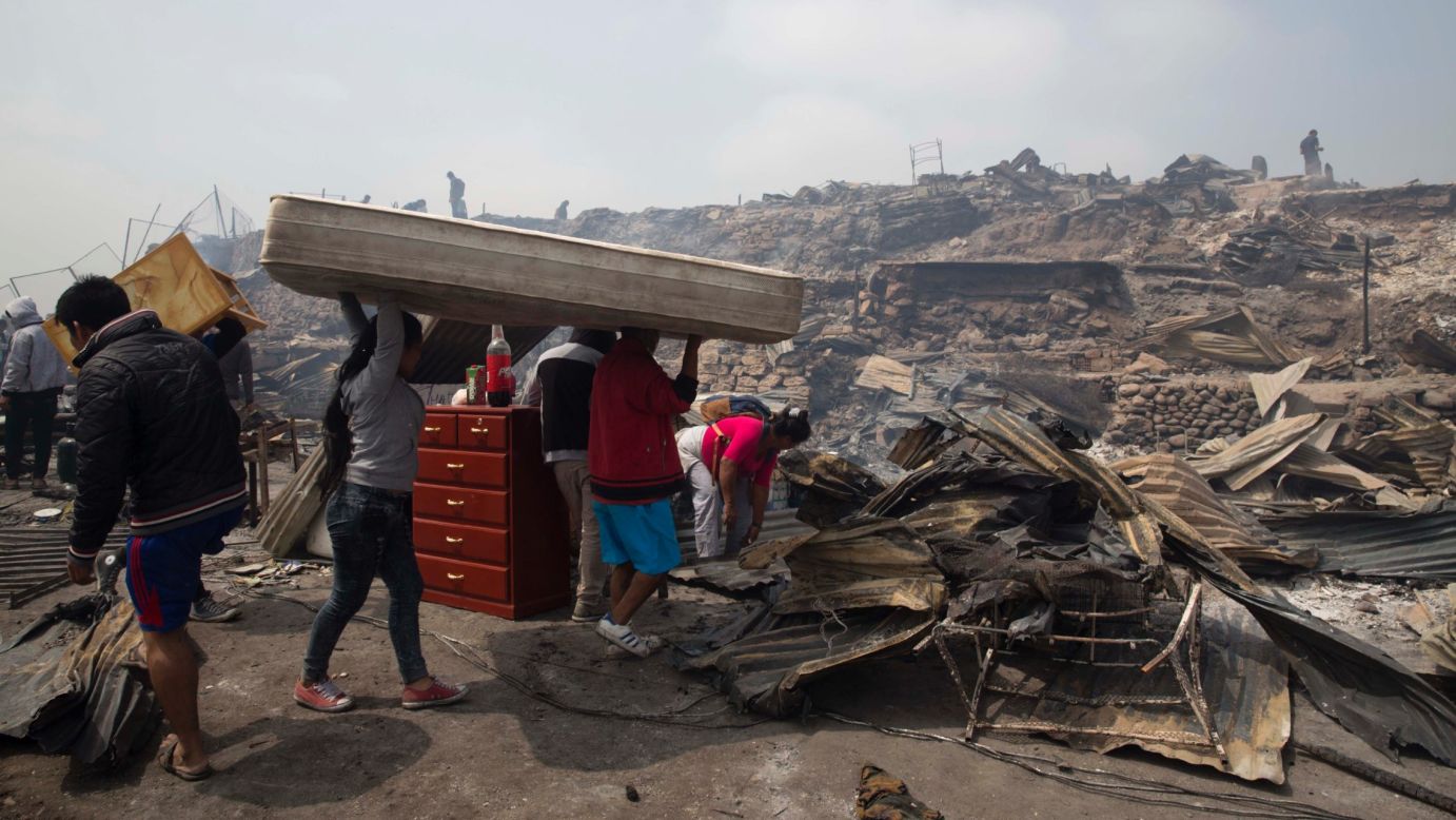 A family salvages a mattress from charred debris after an early morning fire that destroyed hundreds of homes in the indigenous Amazonian community of Cantagallo, in Lima, Peru, on Friday, November 4.