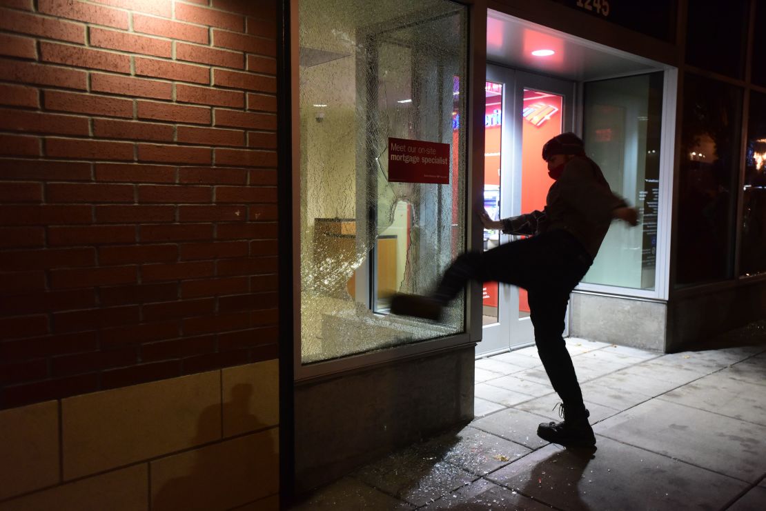 A protester kicks a bank's window during Thurdsay night's protest in Portland.