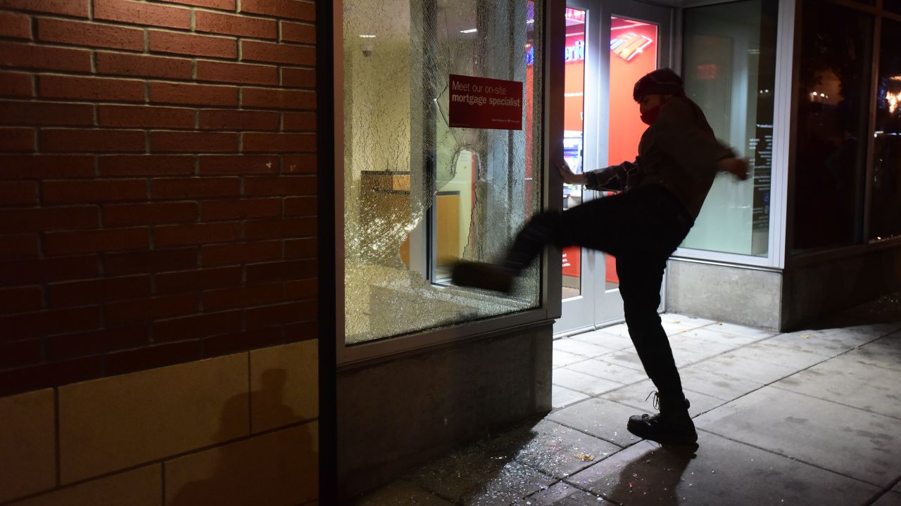 A protester kicks a bank's window during Thurdsay night's protest in Portland.