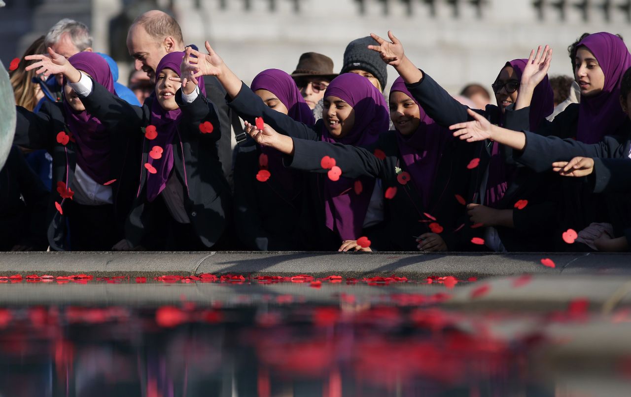 Young students in London scatter poppies into a fountain at Trafalgar Square after observing a two-minute silence in honor of Armistice Day. In advance of Armistice Day, many people in Britain wear a paper red poppy to symbolize the poppies that grew on French and Belgian battlefields during World War I.
