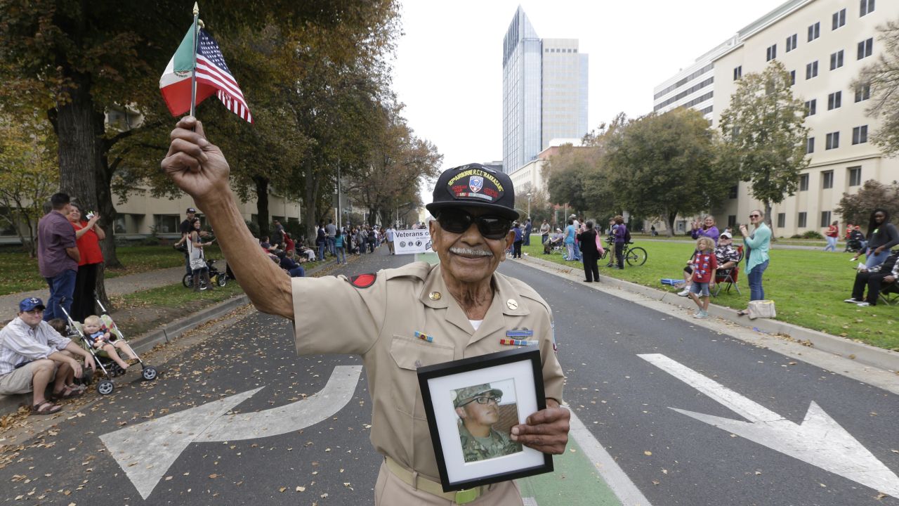 Korean War veteran Oscar Garcia marches during a Veterans Day parade in Sacramento, California, on November 11. He is holding a photo of his 18-year-old grandson, Daniel Garcia, who just graduated from Army boot camp.