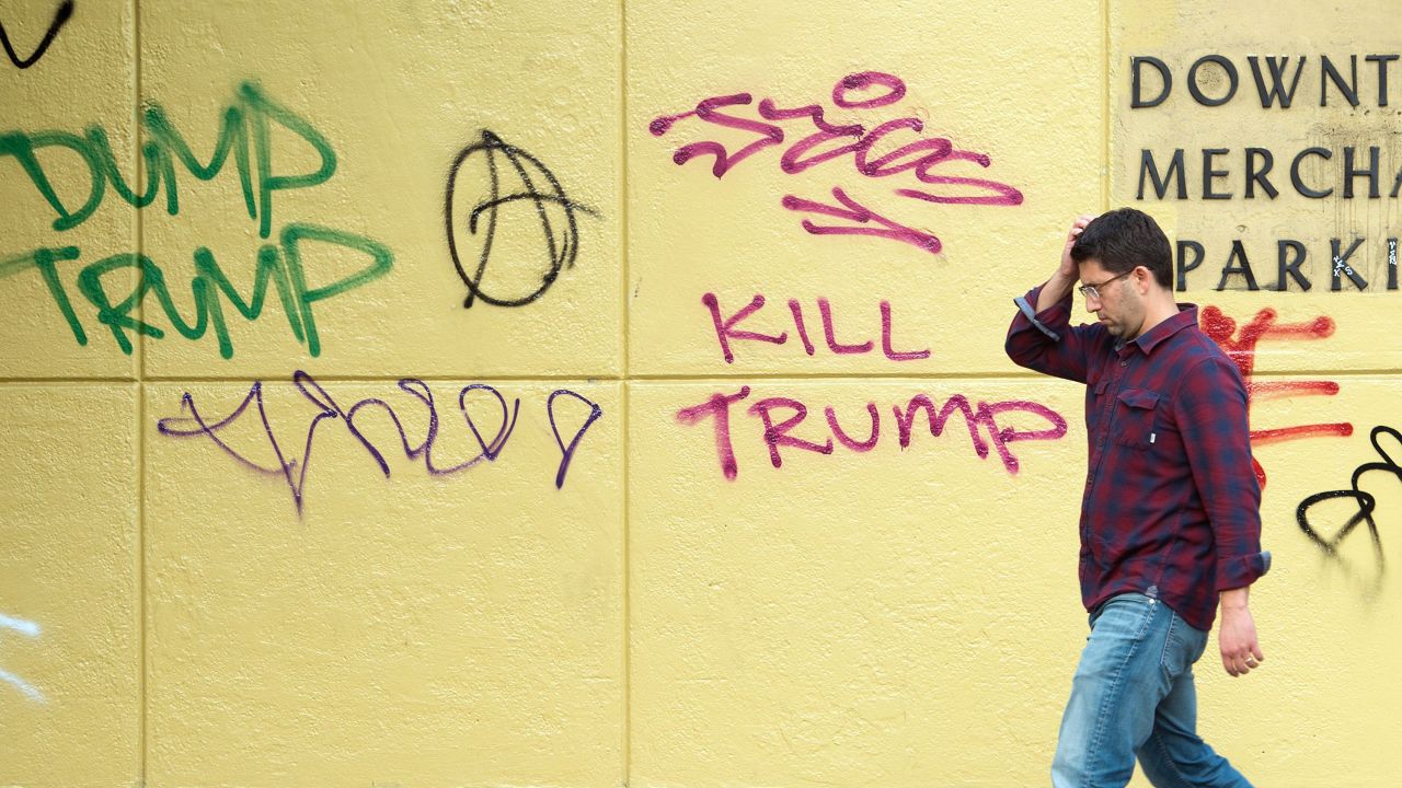 A man walks by anti-Trump graffiti in downtown Oakland, California, on November 11. Thousands of protesters have wreaked havoc on the city during anti-Trump marches, causing vandalism, fires and destruction of property.