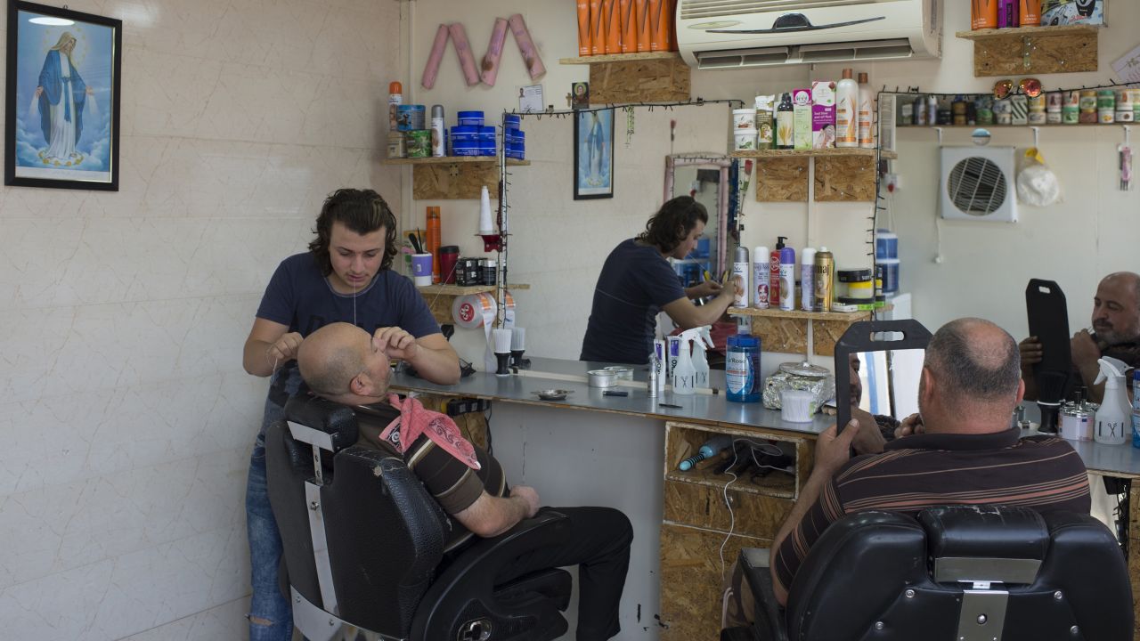 Life goes on at Ashti camp, which has restaurants, coffee shops and stores. Here, a man gets a shave and a haircut at the local barber.