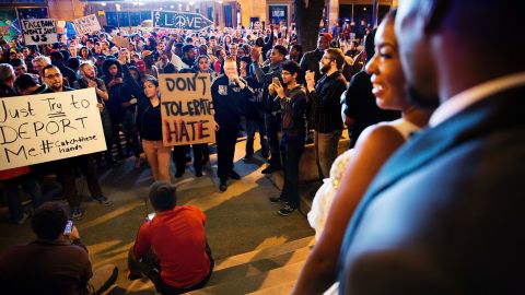 Siedric, right, and Sadio White step out of a hotel during their wedding to look at a protest against President-elect Donald Trump in Atlanta on November 11.