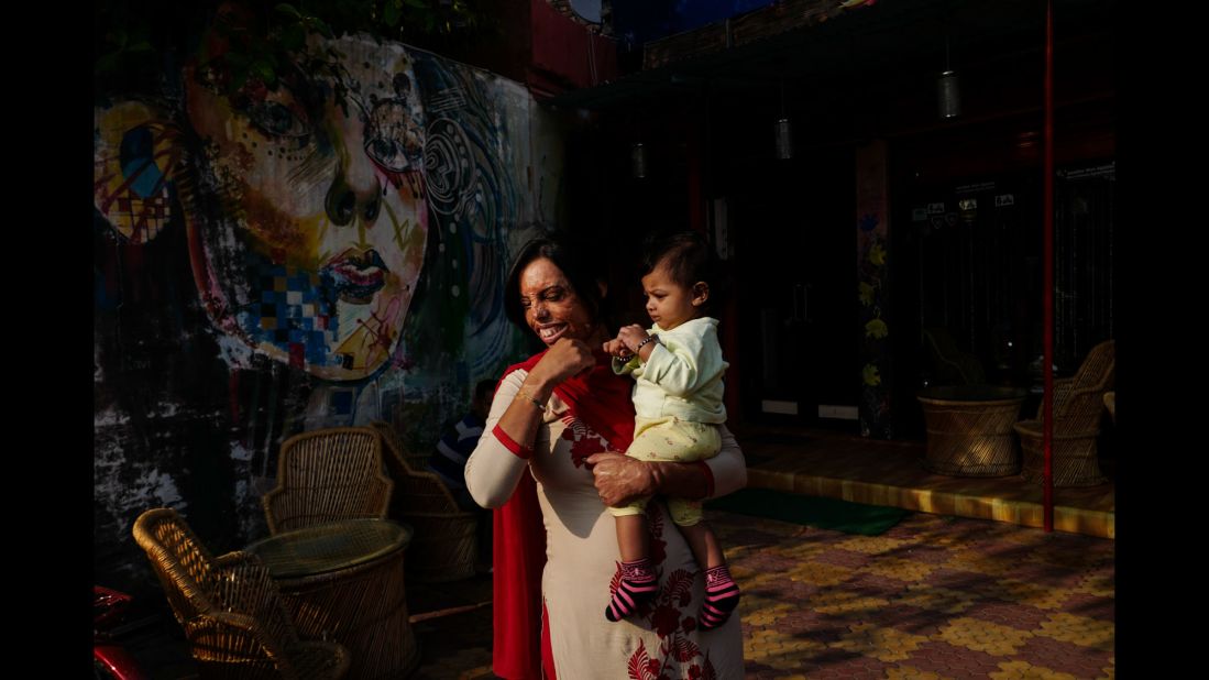 Sonyia, an activist from New Delhi, holds a child at the Sheroes Hangout Cafe in Agra, India. The cafe is staffed by acid attack survivors.