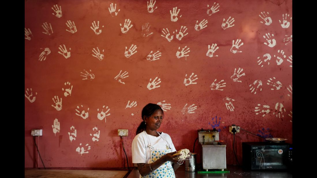 Gita bakes bread in the cafe's kitchen. On the wall are the imprints of all the survivors' hands.