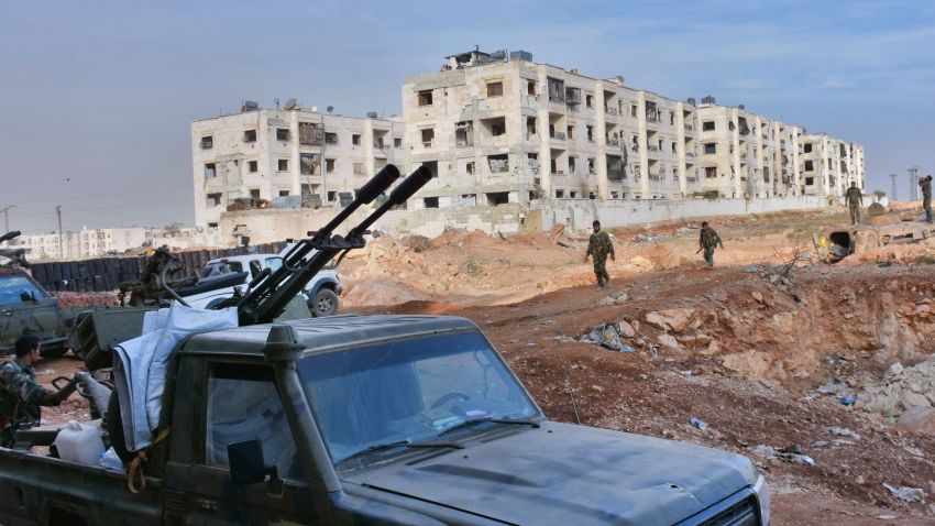 Syrian pro-government forces walk past a pick-up truck mounted with an anti-aircraft machine gun as they hold a position in Aleppo's 1070 district on November 8, 2016, after seizing it from rebel fighters.