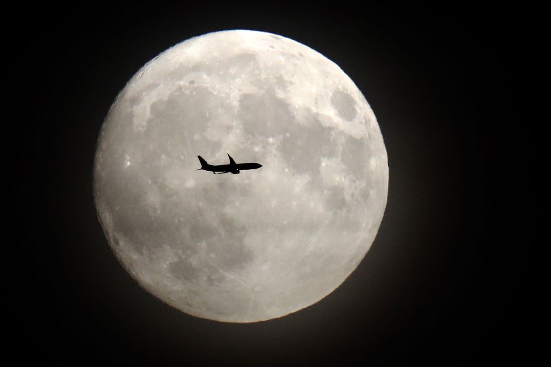 A commerical jet flies in front of the moon on its approach to Heathrow airport on November 13, 2016.