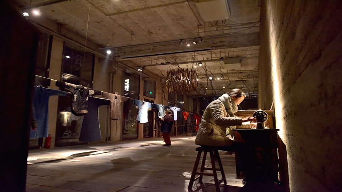 Ma Ke uses a vintage sewing machine next to the clothes exhibited in the Wuyong Space in Beijing.