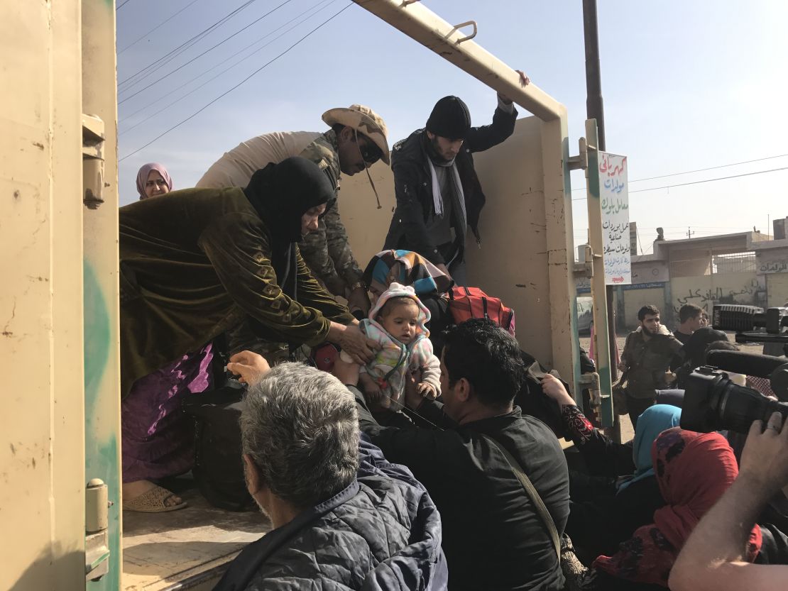 Children are handed to strangers as their family members disembark a truck that has fled the fighting in Mosul. 
