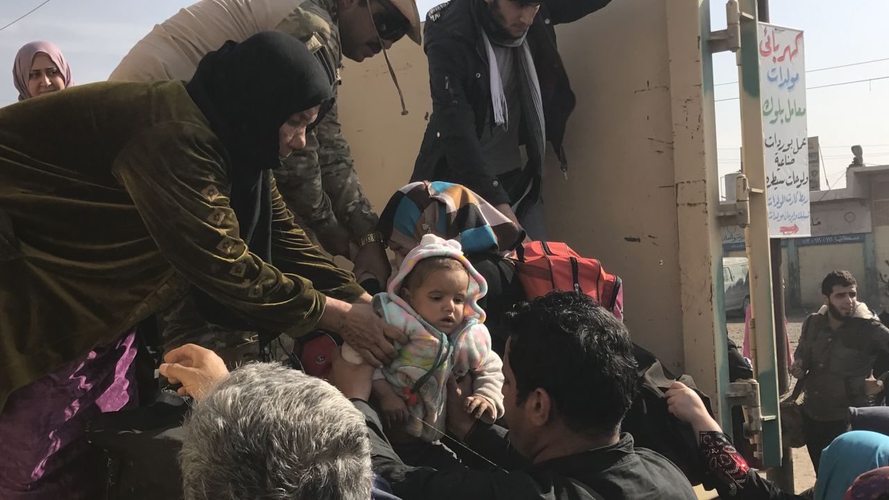 Children are handed to strangers as their family members disembark a truck that has fled the fighting in Mosul. 