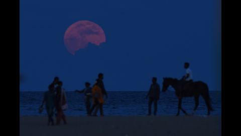 A man rides a horse past people watching the supermoon in Chennai, India, on November 14.