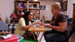 Elizabeth Cosgrove, left, helps Yolanda Solar, 73, who suffers from depression, organize her medications during a home visit on Nov. 3 in San Antonio. Cosgrove is a community outreach worker at a transitional care clinic run by the University of Texas Health Science Center at San Antonio. (Bahram Mark Sobhani for KHN)