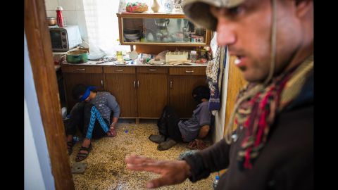 A member of Iraq's special forces guards two suspected ISIS fighters found hiding in a house in Mosul on November 11.