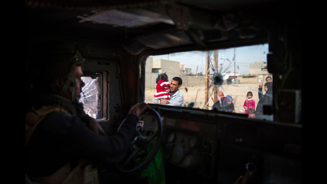 An Iraqi special forces soldier looks on as residents flee Mosul.
