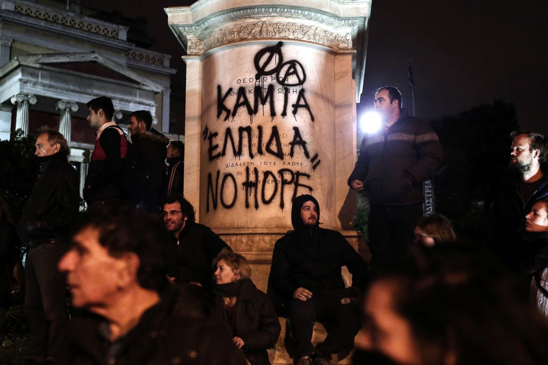 Protesters stand in front of graffiti that reads "No Hope" on Tuesday in Athens.