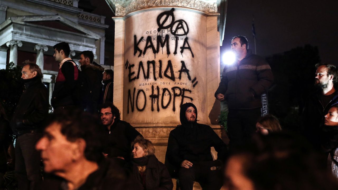 Protesters stand in front of graffiti that reads "No Hope" on Tuesday in Athens.