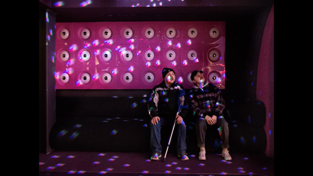 The twins are fascinated by light reflections at a museum's disco room.