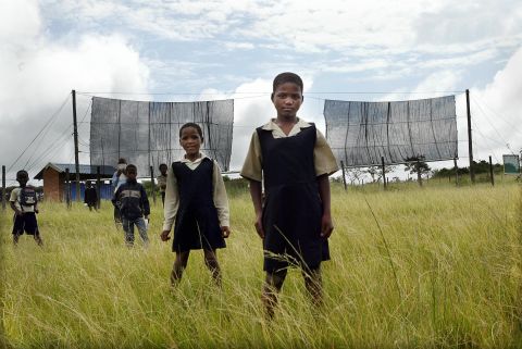 Two nets are used to collect fog and produce water for the village of Taleni in Eastern Cape, South Africa. Pictured here, school pupils from Nomvalo stand in front of the nets in March 2006.