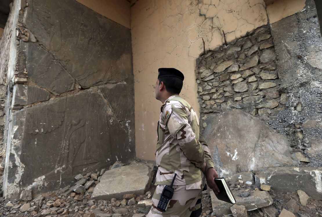 An Iraqi army officer looks at a damaged carved stone slab, destroyed by ISIS militants, in Nimrud.