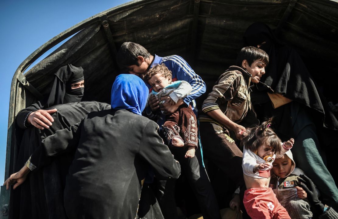 Iraqi families, fleeing the fight to recapture Mosul, board a truck to a displaced persons camp.