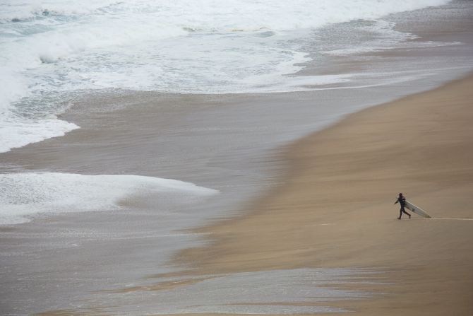 Cotton, here venturing into the water in Portugal, says big-wave surfing can sometimes take days of preparation for just five or six seconds on a wave.