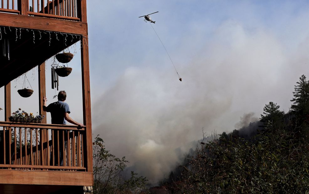 Eric Willey looks on from the porch of his home as a helicopter fights a wildfire in Tate City, Georgia, on Wednesday, November 16. 