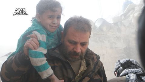 A man carries a child to safety in the wake of the Syrian regime's renewed airstrikes on Aleppo.
