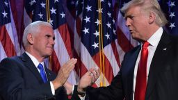 Republican presidential elect Donald Trump (R) reaches to his Vice President elect Mike Pence during election night at the New York Hilton Midtown in New York on November 9, 2016.  