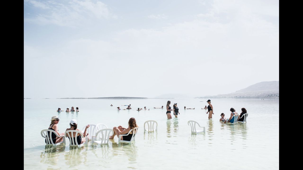 Tourists relax on plastic chairs inside the lake.