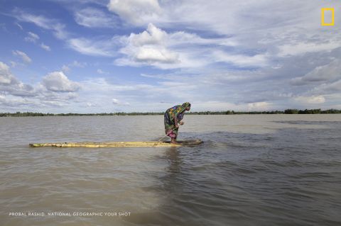 Photo: Probal Rashid. "A flood-affected woman on a raft approaches a boat, searching a dry place to shelter herself in Islampur, Jamalpur, Bangladesh. Bangladesh is one of the countries most vulnerable to the effects of climate change," wrote Rashid. <em>Via National Geographic Your Shot</em>