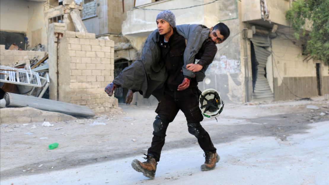 A White Helmets volunteer carries an injured man to safety on Saturday following an airstrike in eastern Aleppo.