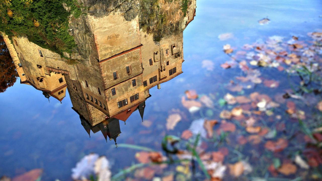 Kriebstein Castle -- one of Germany's most distinctive medieval fortresses -- is reflected in the still water of an autumn puddle.