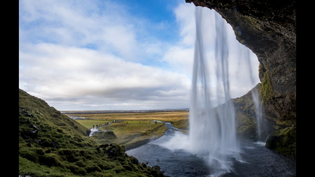 The waters of Seljalandsfoss Waterfall cascade over a cave mouth in Iceland. One of Iceland's premier attractions, the falls allow visitors to observe the Northern Lights through a screen of falling water.  <br />