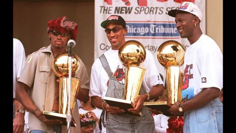 Rodman, left, holds one of the three championship trophies he won with the Bulls.