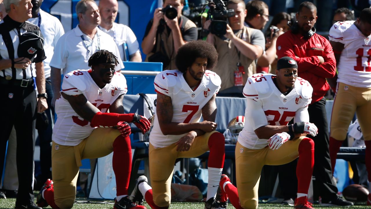 Colin Kaepernick, center, and two teammates kneel for the national anthem at a September 2016 game.