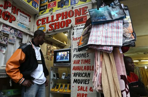 "The digital recycling sector, relating to the life-cycle of all high-tech products, must be completely re-examined, cleaned up, made viable and profitable in the long run throughout the continent," say academics. <br /><br />Pictured: A mobile phone shop worker watches a televised broadcast of the Nelson Mandela memorial service on December 10, 2013 in Johannesburg, South Africa. 