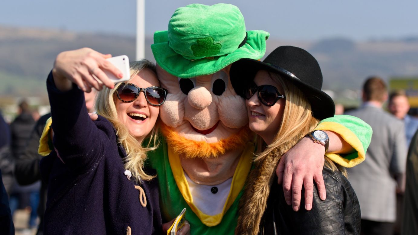 Women in Cheltenham, England, pose with a person in a leprechaun suit on St. Patrick's Day.