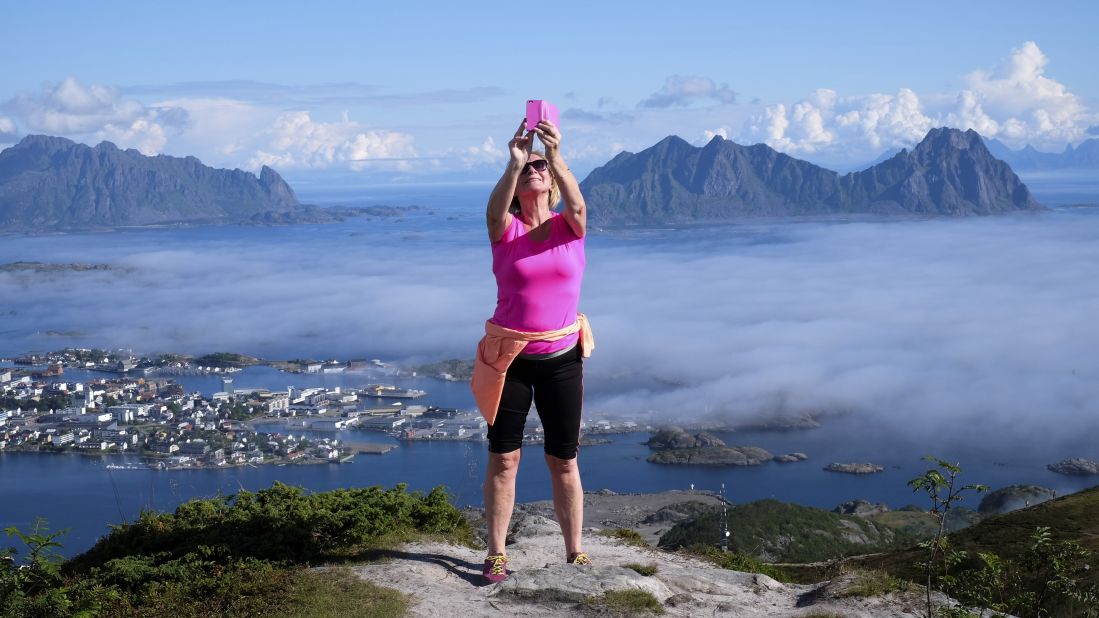 A woman takes a selfie atop a mountain in Norway's Lofoten islands on Sunday, August 21.