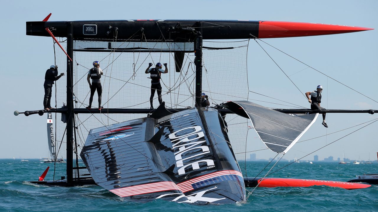 The crew of Oracle Team USA stands on its capsized boat during a practice session in Chicago on Friday, June 10.