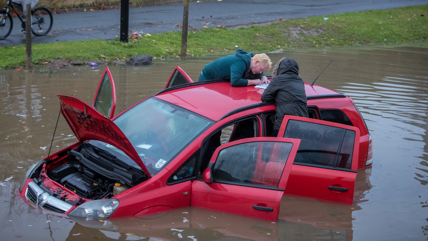People attend to a flooded car after heavy rains in Bristol, England, on Monday, November 21.