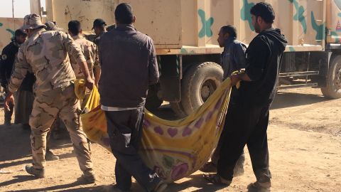 The bodies of civilians are loaded onto a truck for transfer to burial sites.