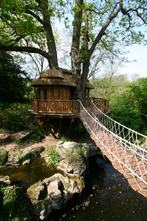 A rope bridge stretches from this "Cliffside Lodge" tree house to its owner's thatched home. The tree house features western red cedar and recessed halogen lighting.