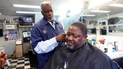 Charleston barbershop owner Thad Miller cuts the hair of customer Joseph Singleton. Both men are paying attention to the two overlapping racially-charged trials of Michael Slager and Dylann Roof.
