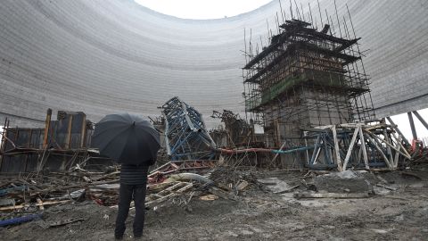 A man looks at the remains of a collapsed platform in a cooling tower at the plant in Fengcheng city, November 25, 2016.