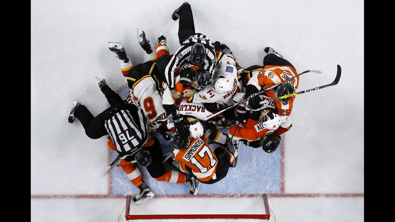 Referees try to break up players during an NHL hockey game between Calgary and Philadelphia on Sunday, November 27.