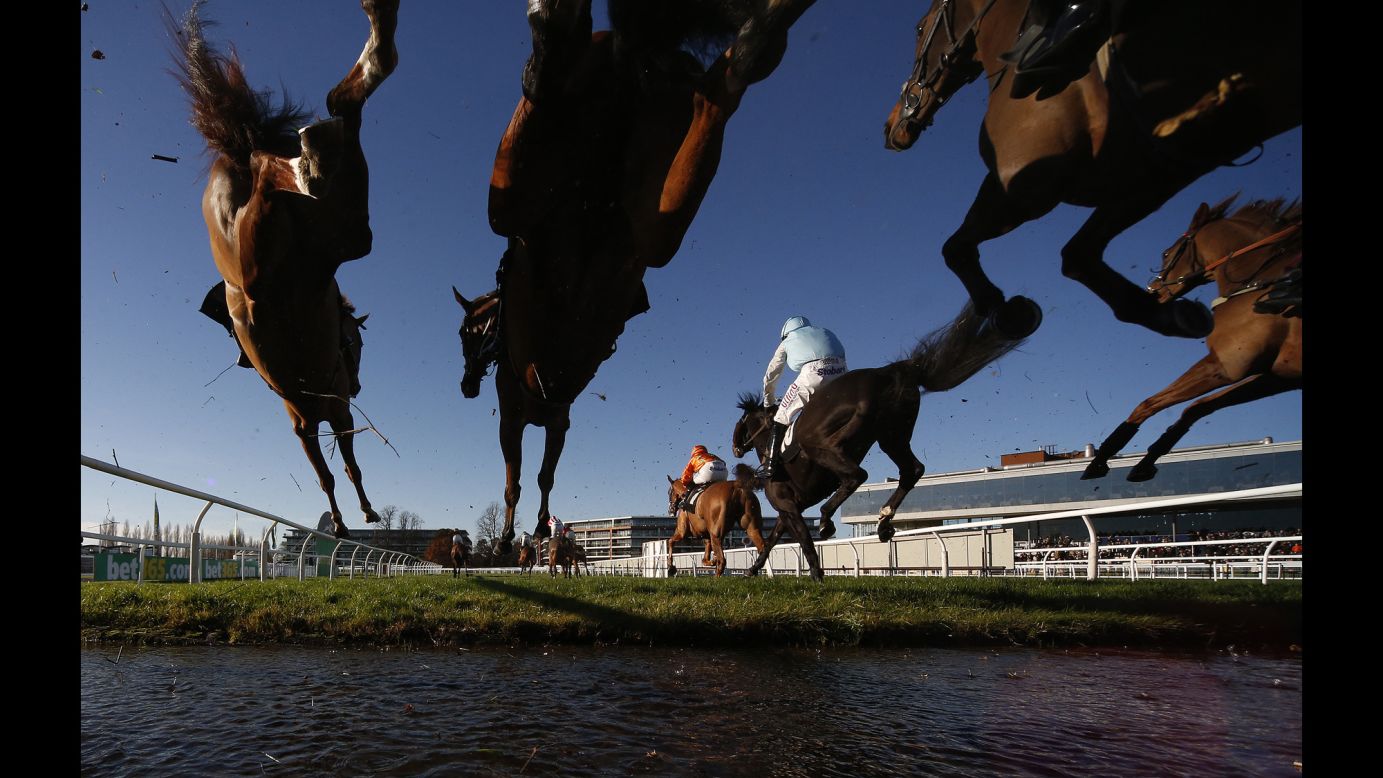 Horses clear a water jump during a steeplechase race in Newbury, England, on Friday, November 25.