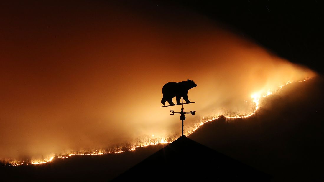 Flames from the Rock Mountain Fire silhouette a weather vane north of Clayton, Georgia, on Monday, November 21.