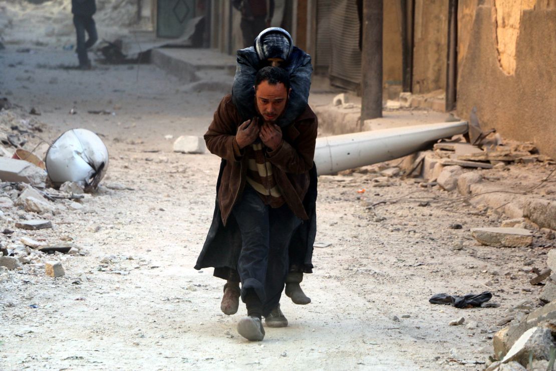 A man helps evacuate a wounded victim after airstrikes in al-Shear, Aleppo, on Monday. 